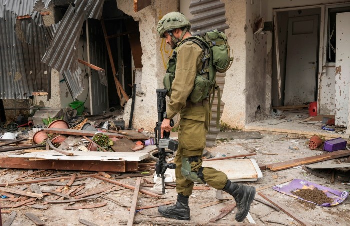 An Israeli soldier walks past a house damaged during the Hamas attack on Kibbutz Kfar Aza