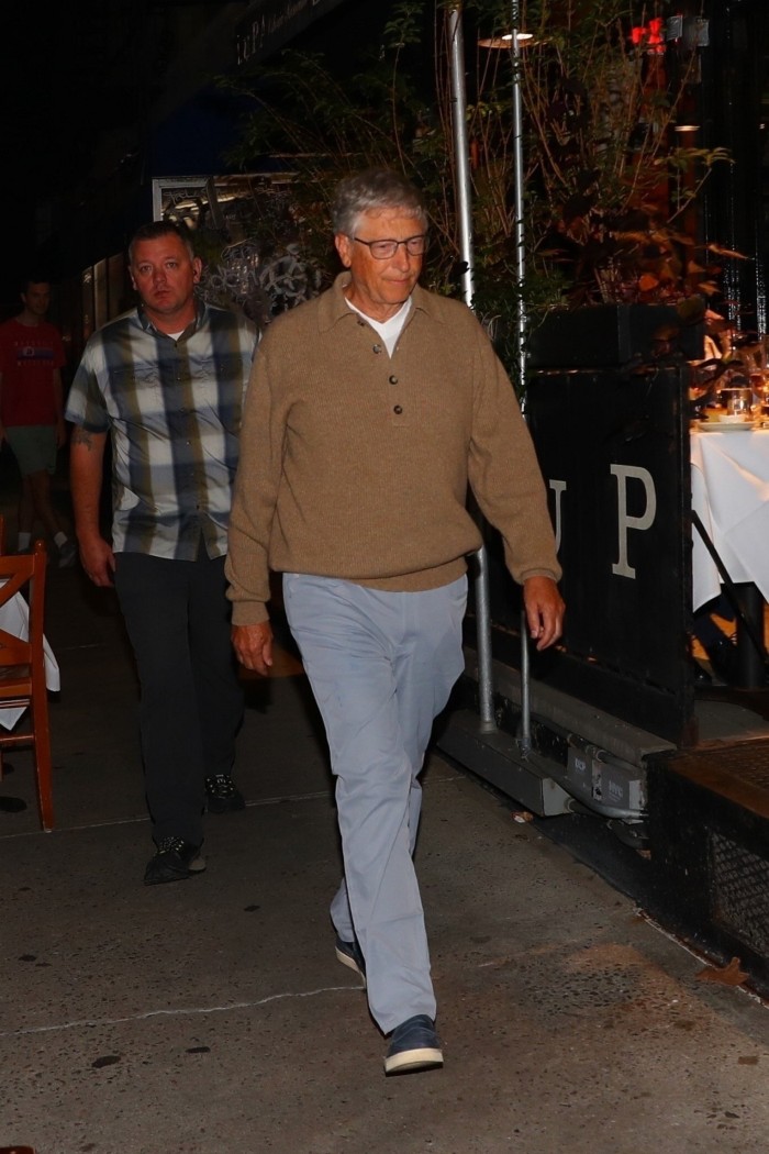 Bill Gates in sneakers, blue-grey trousers and beige sweatshirt over white T-shirt 