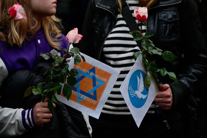 People holding flowers and placards during a vigil