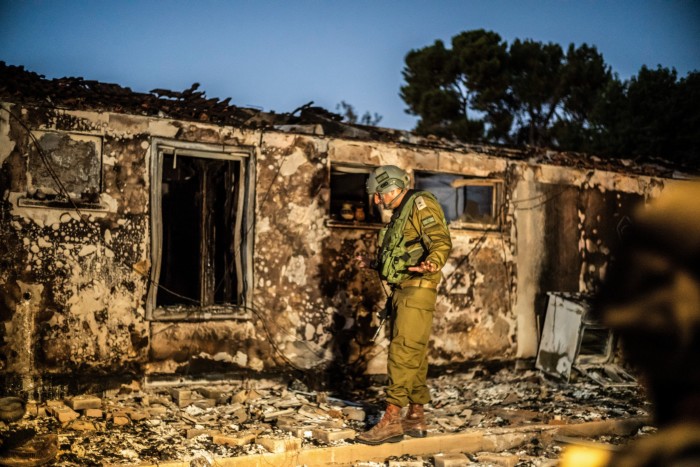 An Israeli soldier inspects a destroyed house in Kibbutz Be’eri after the army regained control