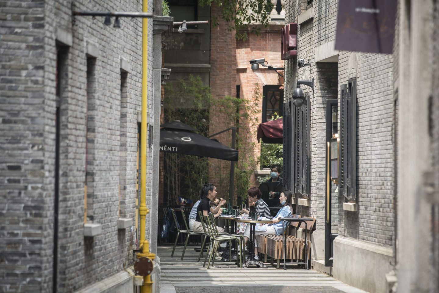 Customers sit and dine in the open air area of a restaurant in the Xintiandi retail district in Shanghai, China.