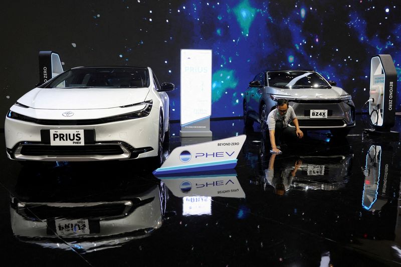 © Reuters. FILE PHOTO: A man sweeps the floor near a Toyota Prius PHEV and a Toyota BZ4X during the Indonesia International Motor Show in Tangerang, Indonesia, July 18, 2024. REUTERS/Aging Dinar Olfiana/File Photo